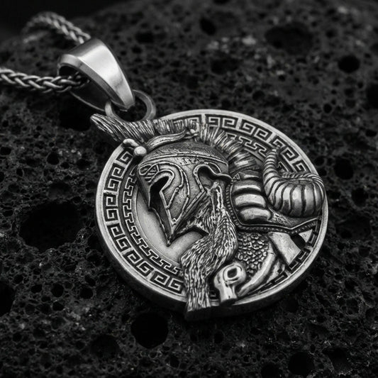 Oxidized sterling silver Viking warrior pendant on textured volcanic rock, Norse helmet profile relief with Greek key border, macro studio shot