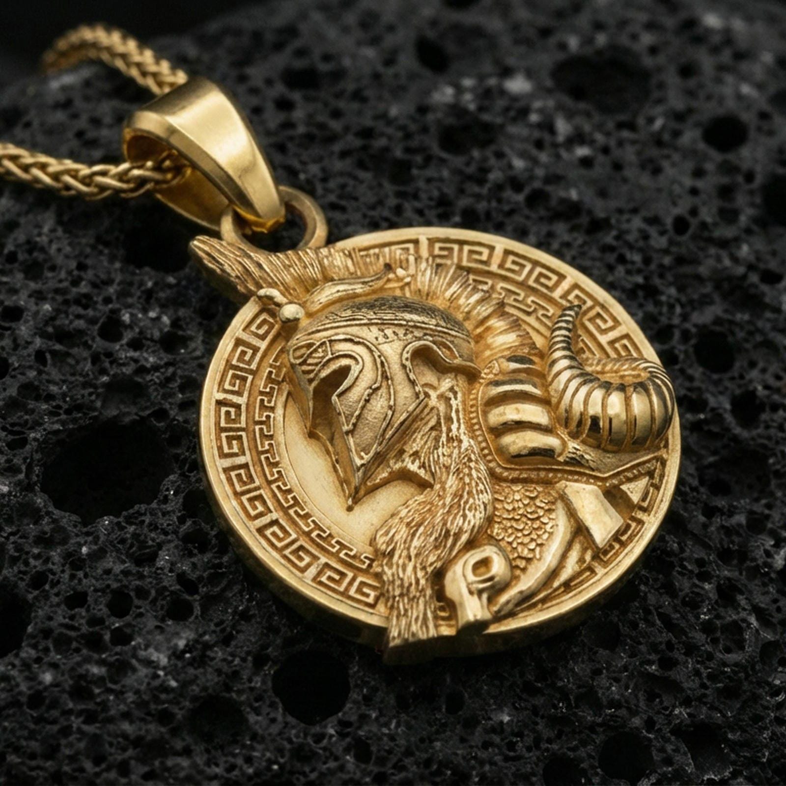Gold plated Viking warrior coin pendant on porous volcanic rock backdrop, bold Norse helmet design and patterned border, high-contrast lighting