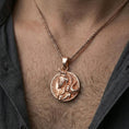 Load image into Gallery viewer, Rose gold plated Viking warrior coin pendant worn on neck, detailed warrior relief, clean lifestyle framing with dark shirt contrast
