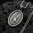 Load image into Gallery viewer, Oxidized sterling silver Our Lady of Guadalupe oval pendant on textured volcanic rock, raised Virgin Mary relief with radiant frame, macro studio shot
