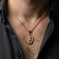 Load image into Gallery viewer, Rose gold plated Guadalupe oval pendant worn on neck, detailed Virgin Mary relief, clean lifestyle framing with dark shirt contrast
