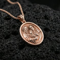 Load image into Gallery viewer, Rose gold plated Holy Family oval pendant on matte volcanic stone, intricate religious engraving of Mary Joseph and Jesus, sharp macro focus
