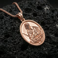 Load image into Gallery viewer, Rose gold plated Jesus Christ oval pendant on matte volcanic stone, intricate religious engraving with draped robe detail, sharp macro focus
