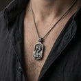 Load image into Gallery viewer, Oxidized sterling silver Holy Family pendant worn on neck on a braided chain, centered chest framing, moody lifestyle studio shot
