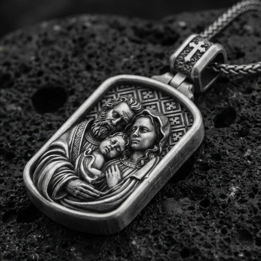 Oxidized sterling silver Holy Family pendant on textured volcanic rock, rectangular medallion with Mary Joseph and Child relief, macro studio shot