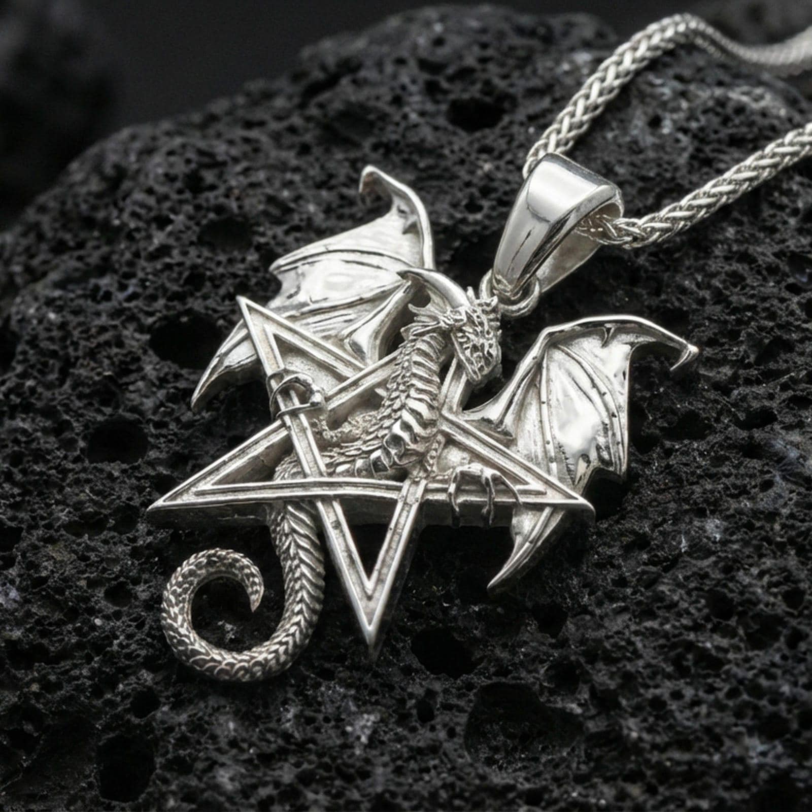 Polished silver dragon pentagram necklace on dark volcanic stone, crisp wing detail and geometric star outline, premium close-up composition