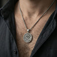 Load image into Gallery viewer, Oxidized 925 sterling silver Chinese dragon pendant worn on neck on a braided chain, centered chest framing, moody lifestyle studio shot
