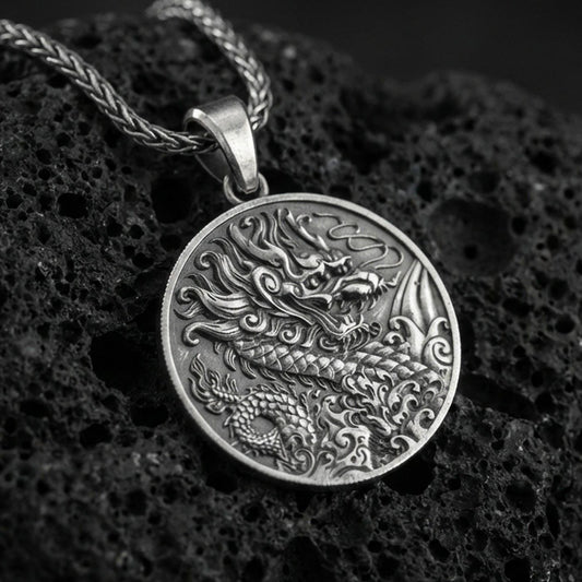 Oxidized 925 sterling silver Chinese dragon round pendant on textured volcanic rock, intricate Asian dragon engraving and wave motifs, macro studio shot