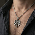 Load image into Gallery viewer, Oxidized sterling silver dragon cross pendant worn on neck on a braided chain, centered chest framing, moody lifestyle studio shot

