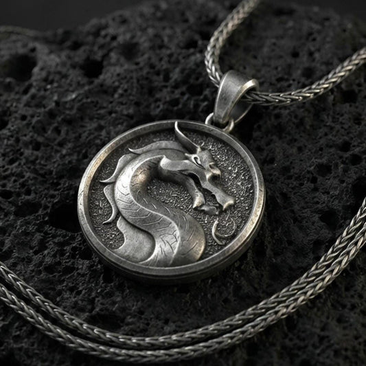 Oxidized sterling silver Mortal Kombat dragon pendant on volcanic rock, round medallion with raised dragon emblem, macro studio lighting