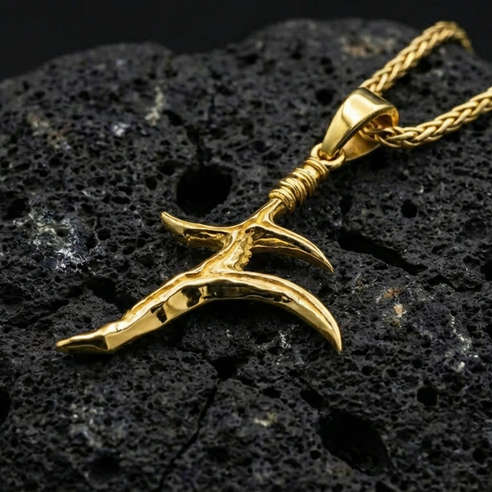 Gold plated black knife charm necklace on dark volcanic rock, Elden Ring inspired dagger pendant, premium macro lighting