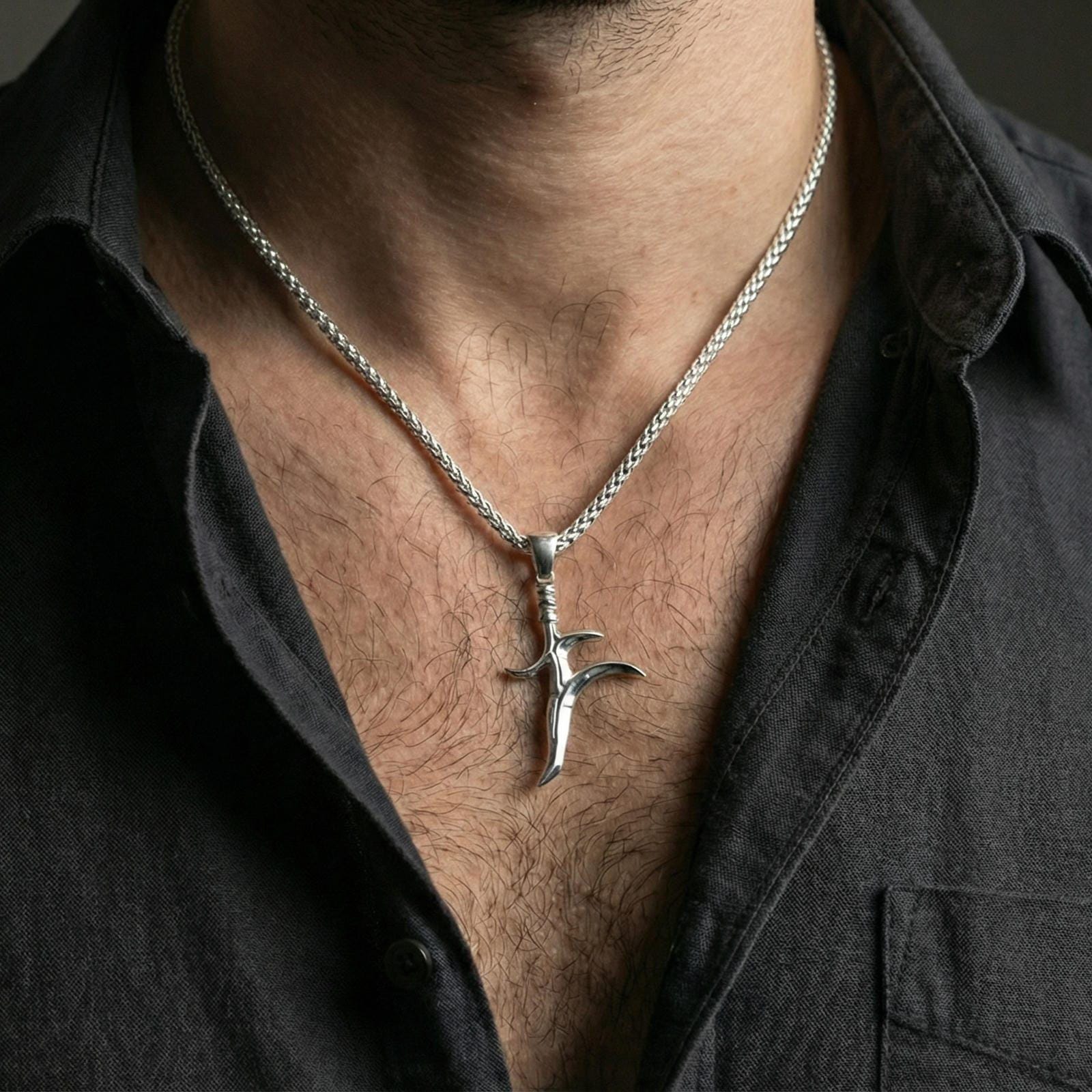 Polished silver black knife dagger pendant worn on neck, minimalist fantasy charm necklace, close lifestyle crop