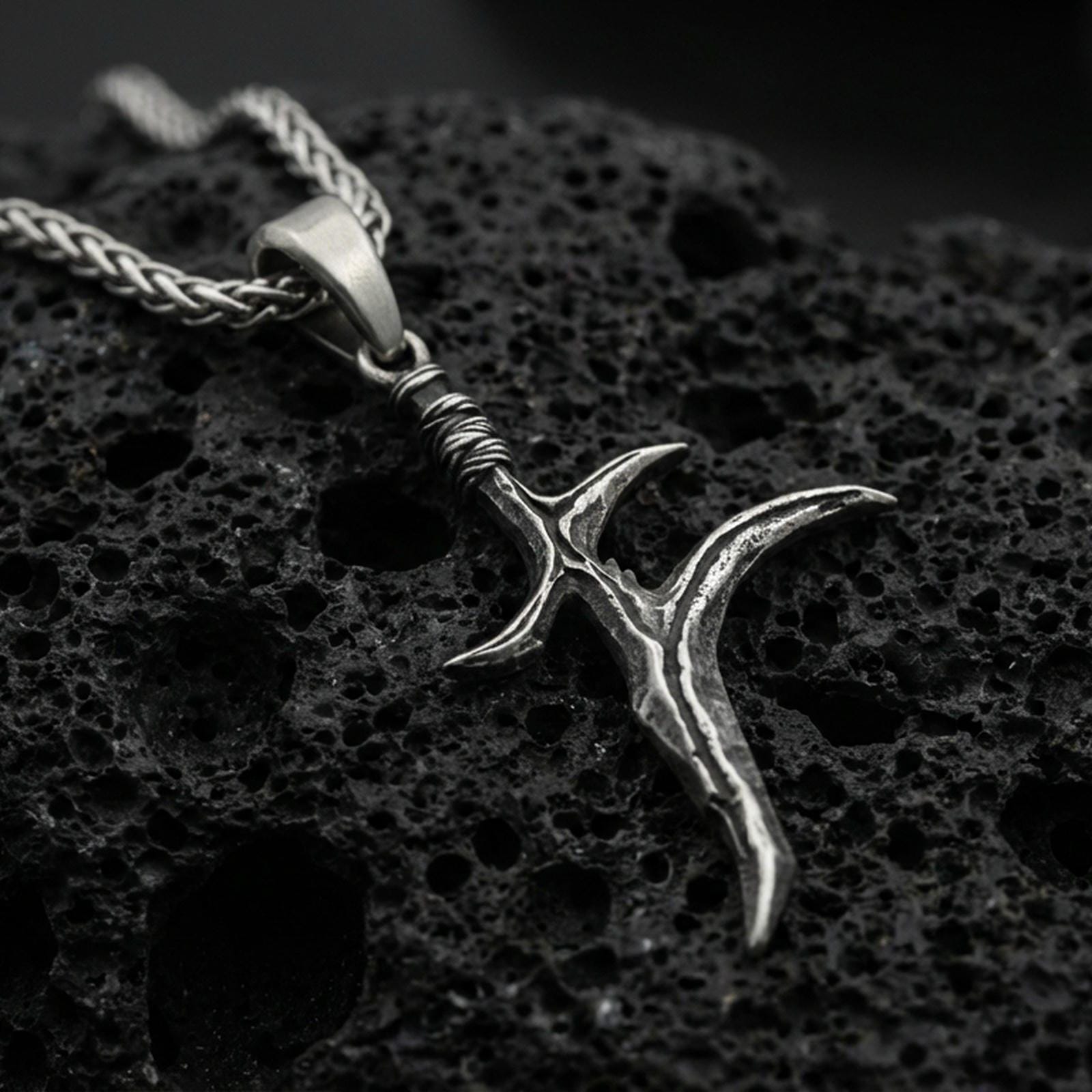 Oxidized sterling silver black knife charm pendant on volcanic rock, Elden Ring inspired dagger necklace, macro product photo