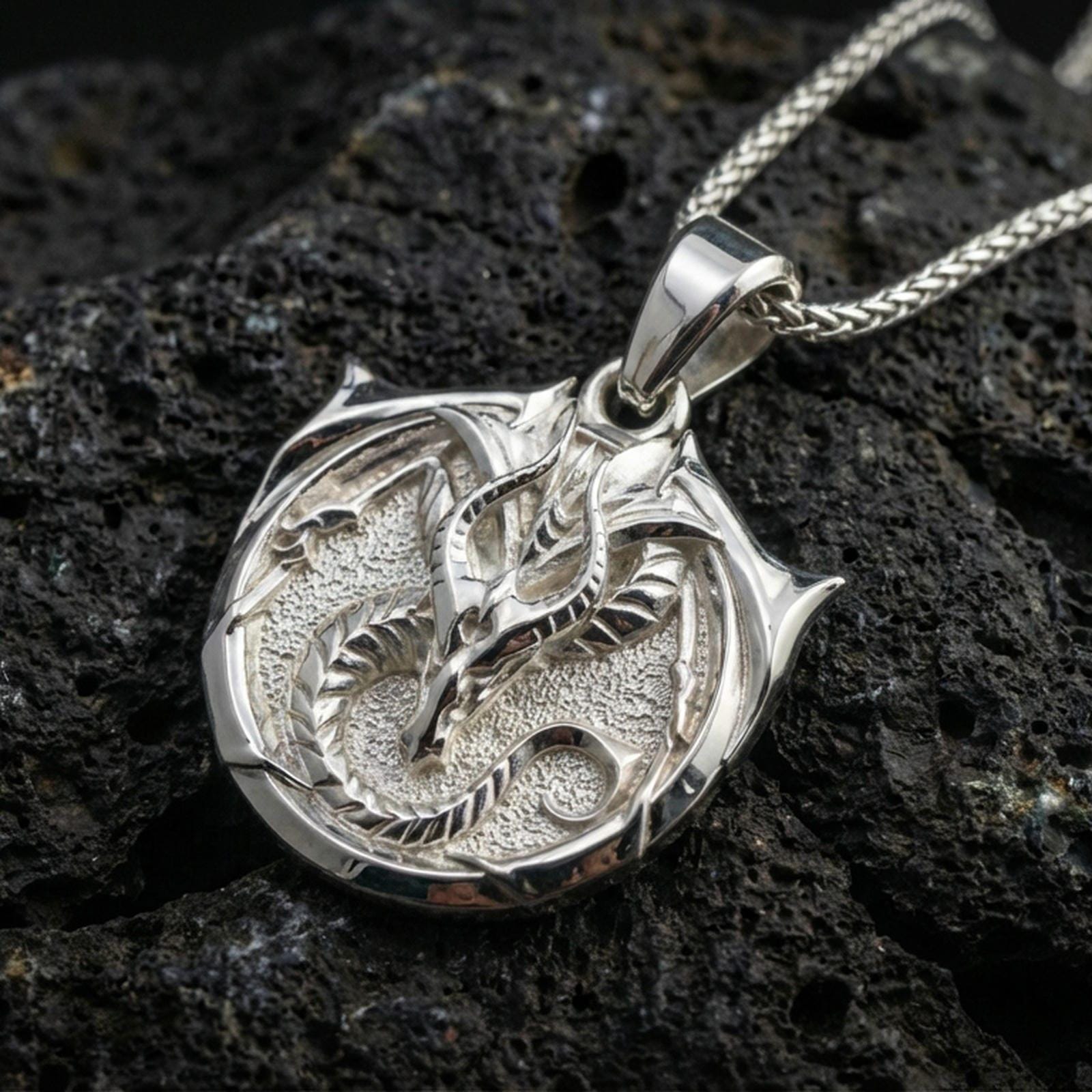 Polished silver dragon pendant on volcanic rock, sharp horned dragon head relief fantasy charm necklace