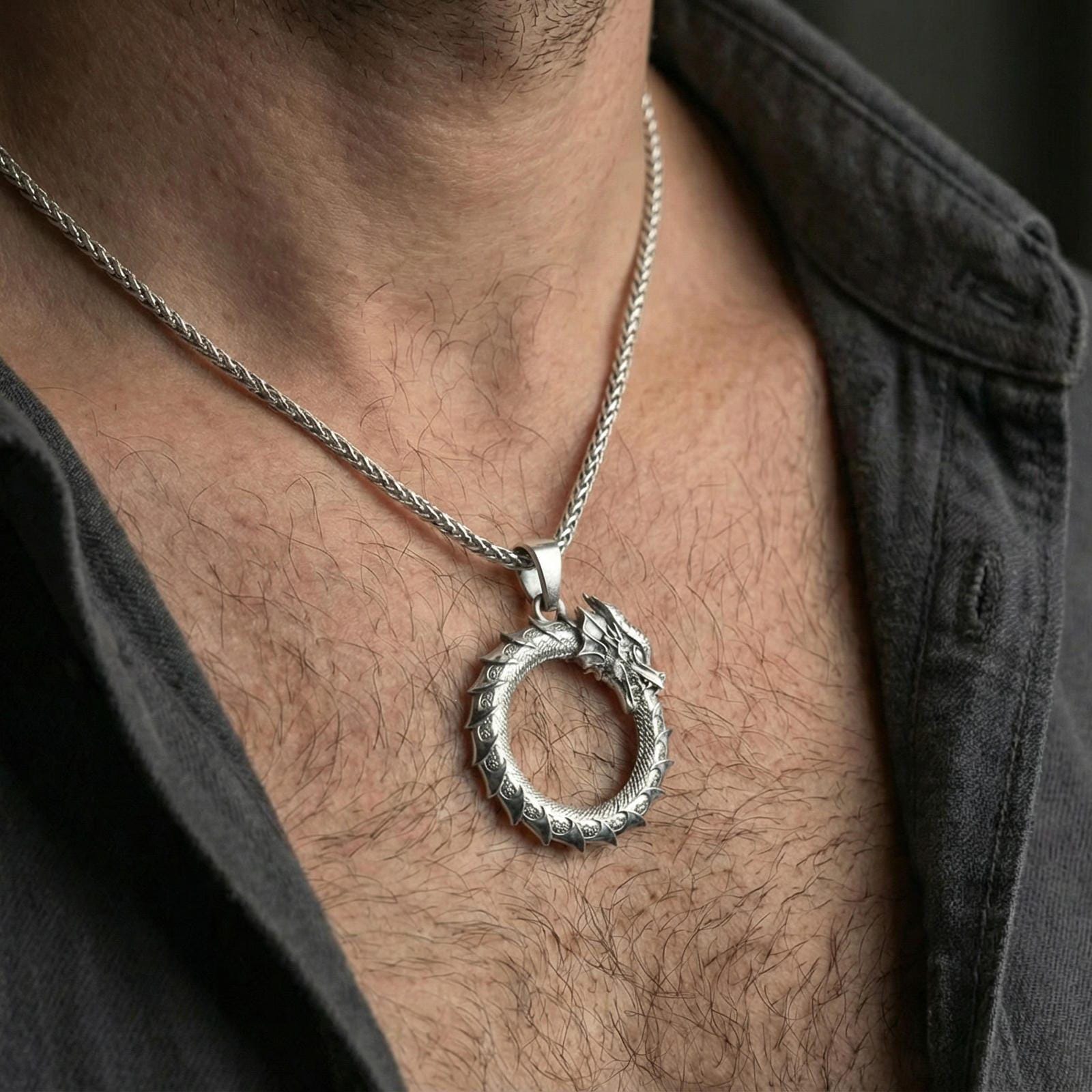 Polished silver ouroboros dragon circle necklace worn on neck, detailed scale texture pendant leading the look, clean lifestyle crop