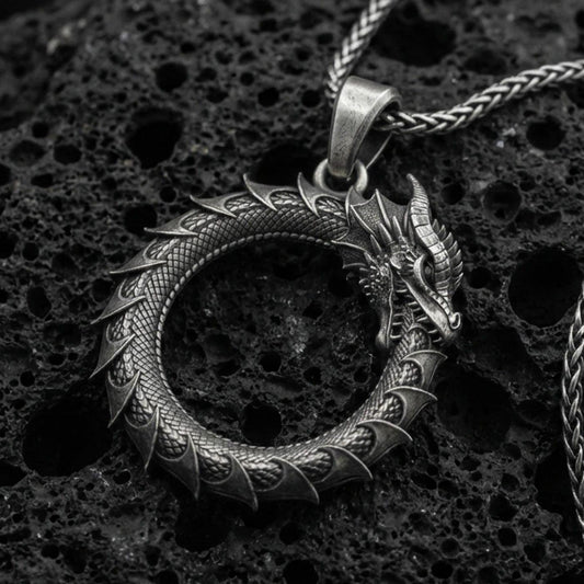 Oxidized sterling silver ouroboros dragon pendant on volcanic rock, tail-devourer eternity symbol necklace, macro close-up