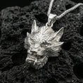Load image into Gallery viewer, Polished silver Chinese dragon head charm on porous volcanic stone, sharp scale and whisker details, product photo
