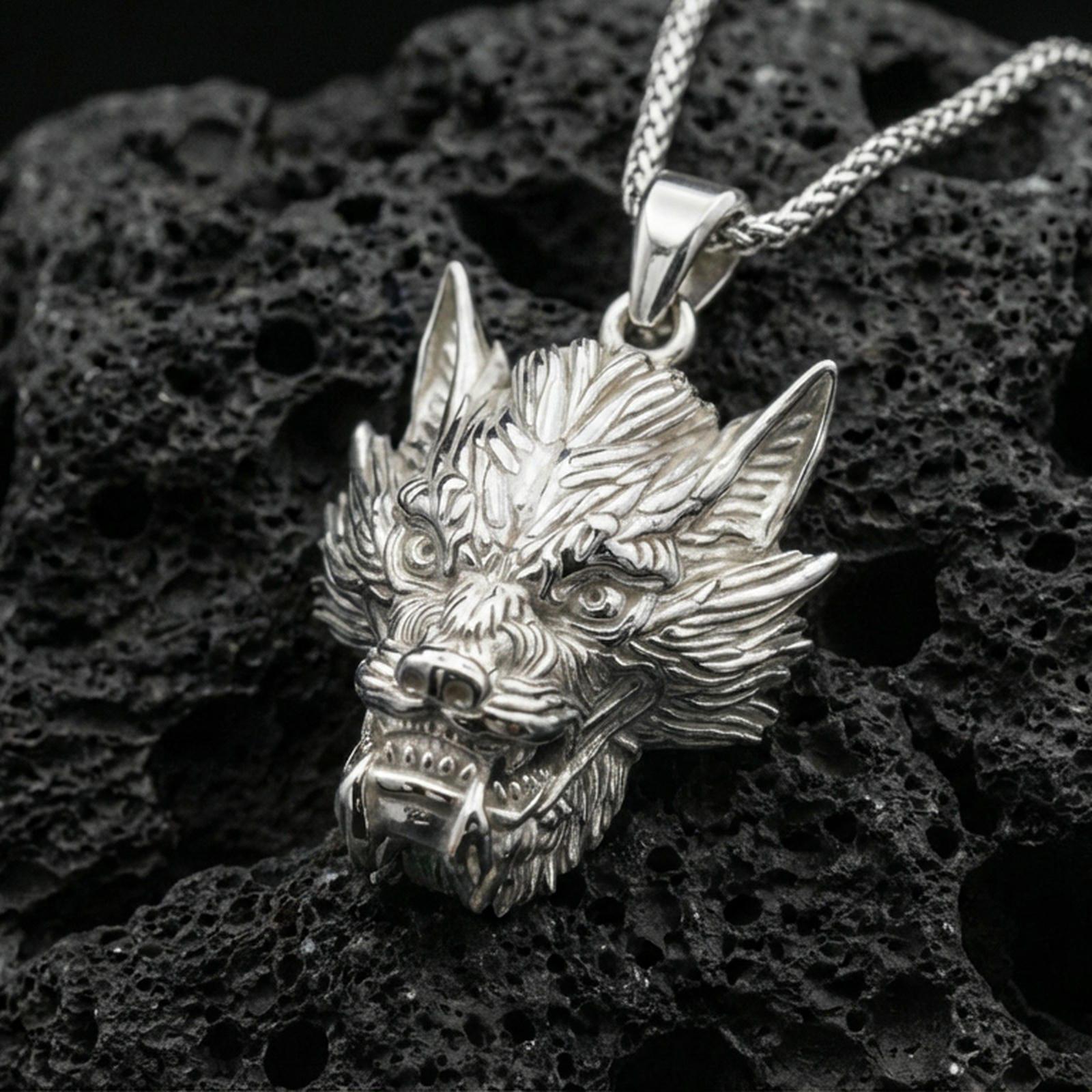 Polished silver Chinese dragon head charm on porous volcanic stone, sharp scale and whisker details, product photo