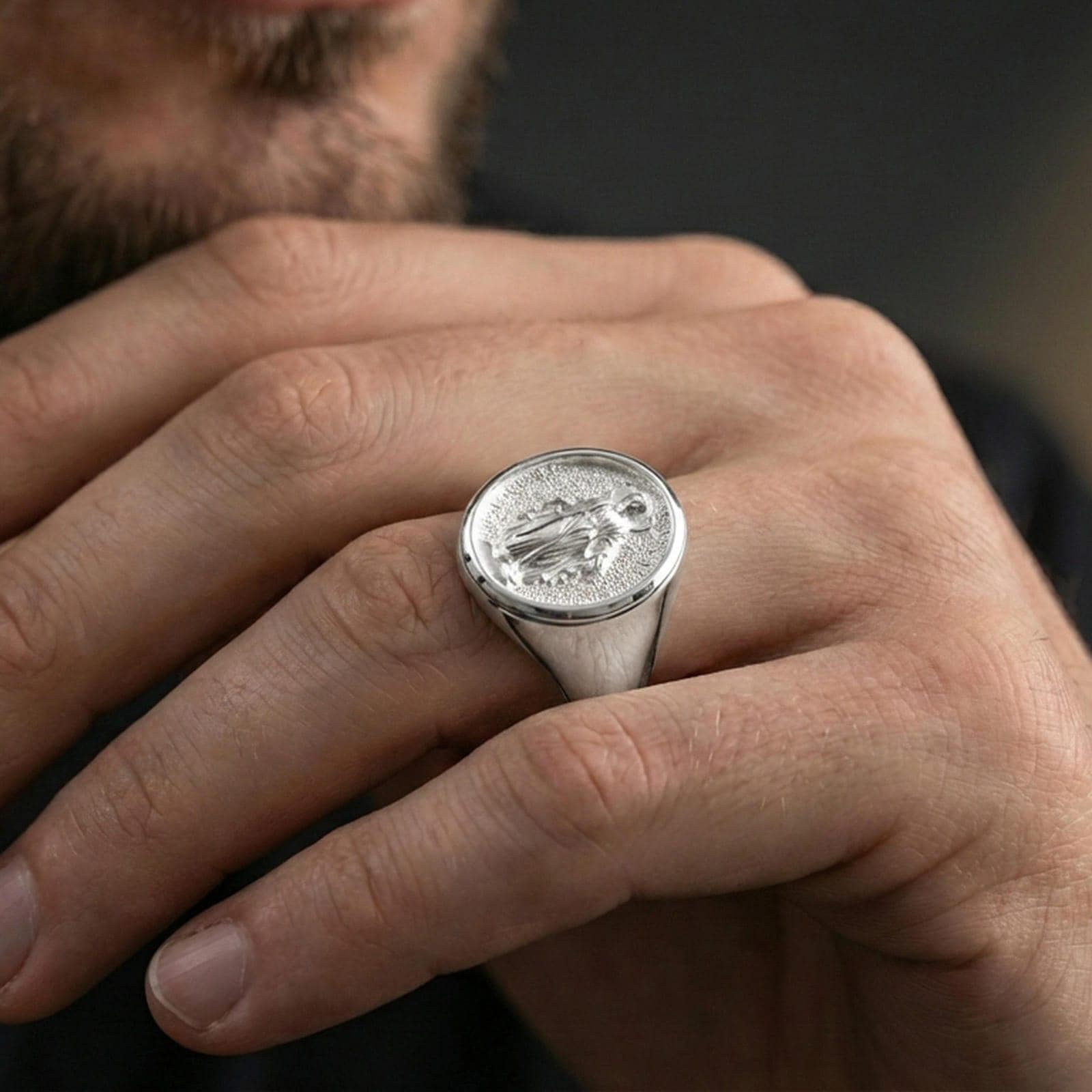 Polished silver Virgin Mary oval signet ring worn on finger, religious statement ring, clean lifestyle crop