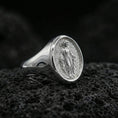 Load image into Gallery viewer, Polished silver Virgin Mary oval signet ring on porous volcanic stone, Catholic devotional ring, studio close-up
