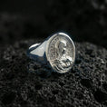 Load image into Gallery viewer, Polished silver Virgin Mary oval signet ring on porous volcanic stone, reflective religious ring, studio close-up
