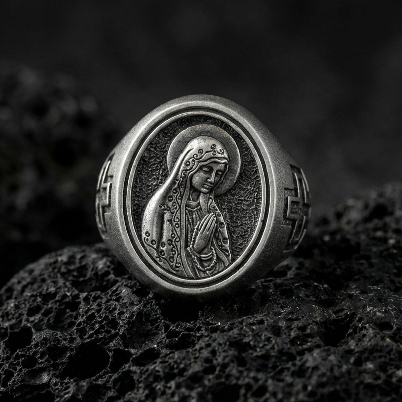 Oxidized sterling silver Our Lady of Guadalupe signet ring on volcanic rock, oval Virgin Mary relief, macro close-up