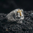 Load image into Gallery viewer, Polished silver skull ring with cross on porous volcanic stone, engraved feather wings, bold biker gothic ring close-up
