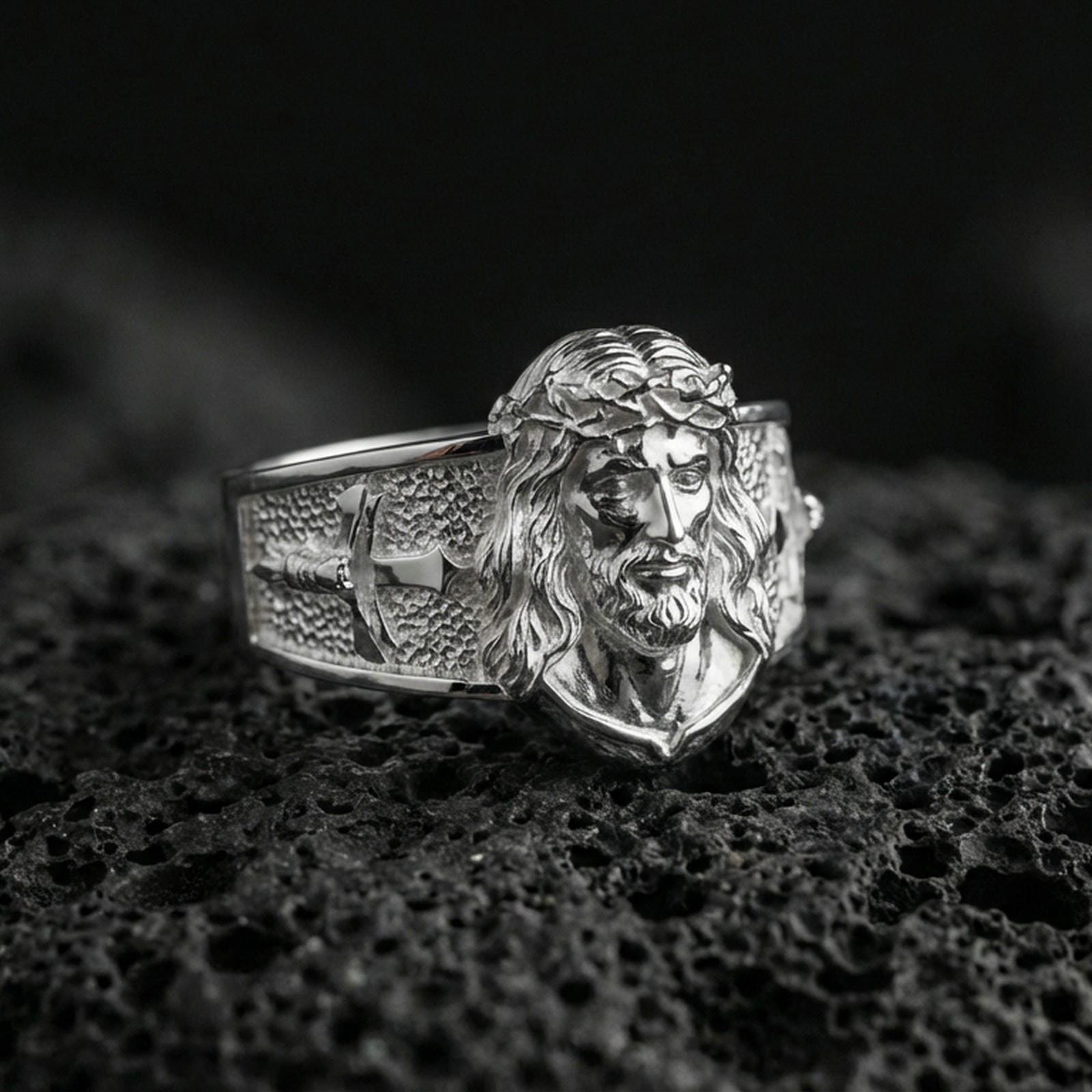 Polished silver Jesus Christ ring on porous volcanic stone, detailed Christ head engraving, Christian mens ring close-up