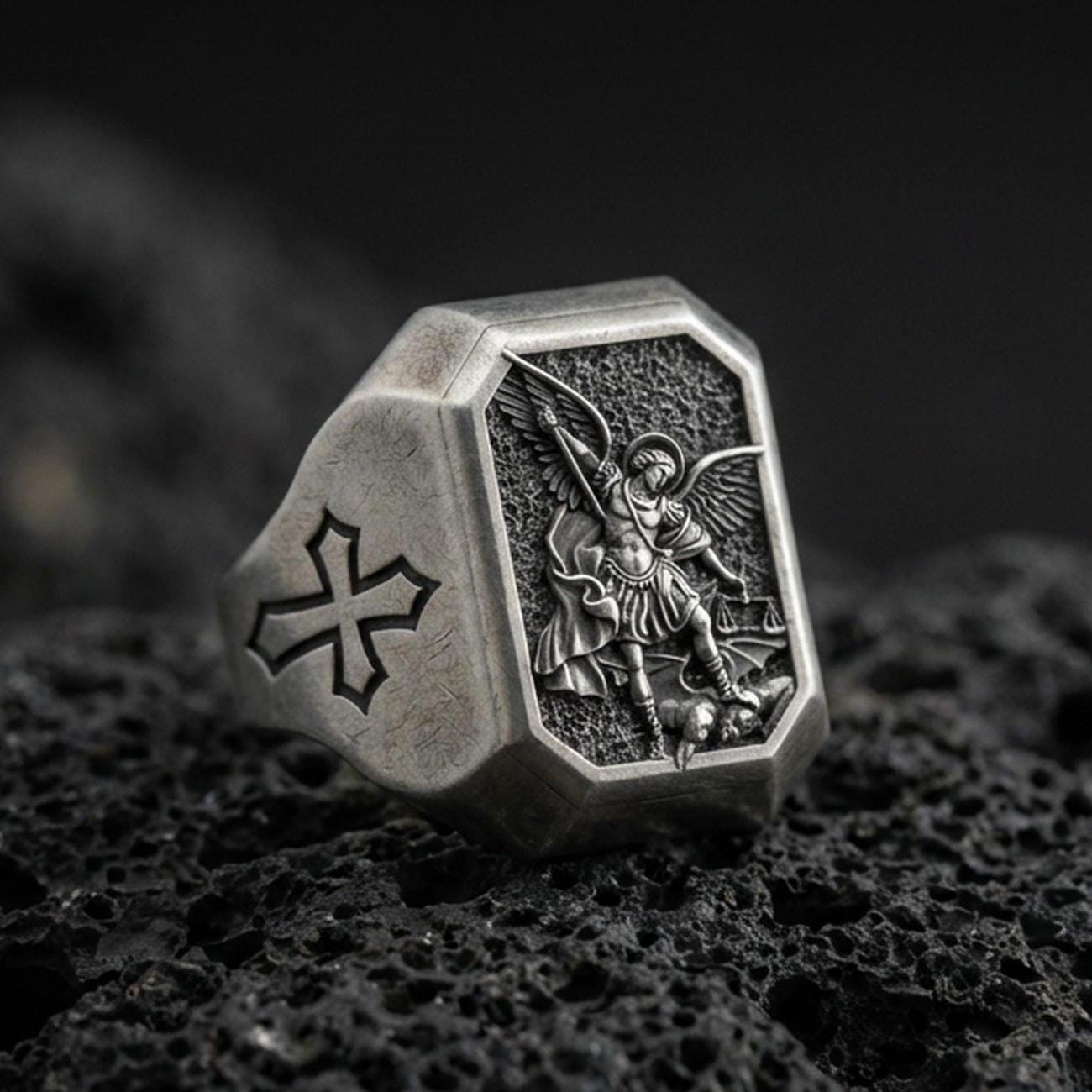 Oxidized sterling silver Saint Michael signet ring on volcanic rock, archangel warrior relief, Knights Templar cross side
