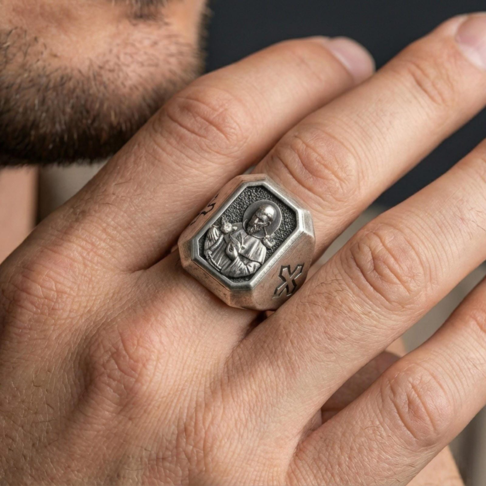 Oxidized sterling silver St Francis ring worn on finger, saint relief signet, cross side engraving close-up