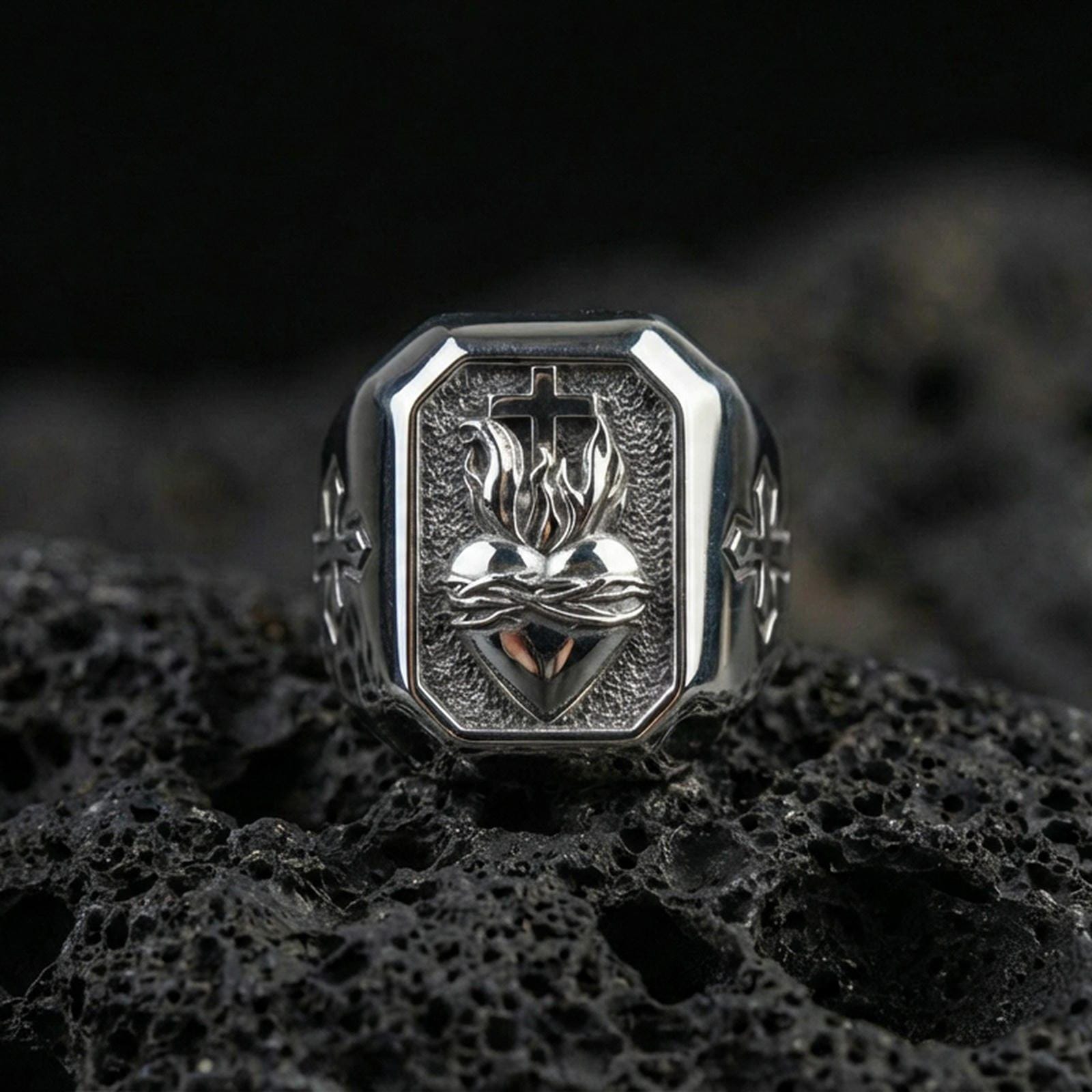 Polished silver cross heart signet ring on porous volcanic stone, sacred heart motif relief, Christian jewelry