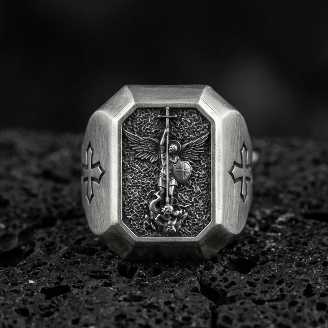 Oxidized sterling silver St Michael archangel signet ring on volcanic rock, winged warrior relief, cross shoulder engravings