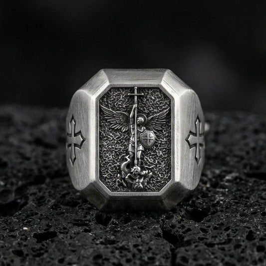 Oxidized sterling silver St Michael archangel signet ring on volcanic rock, winged warrior relief, cross shoulder engravings