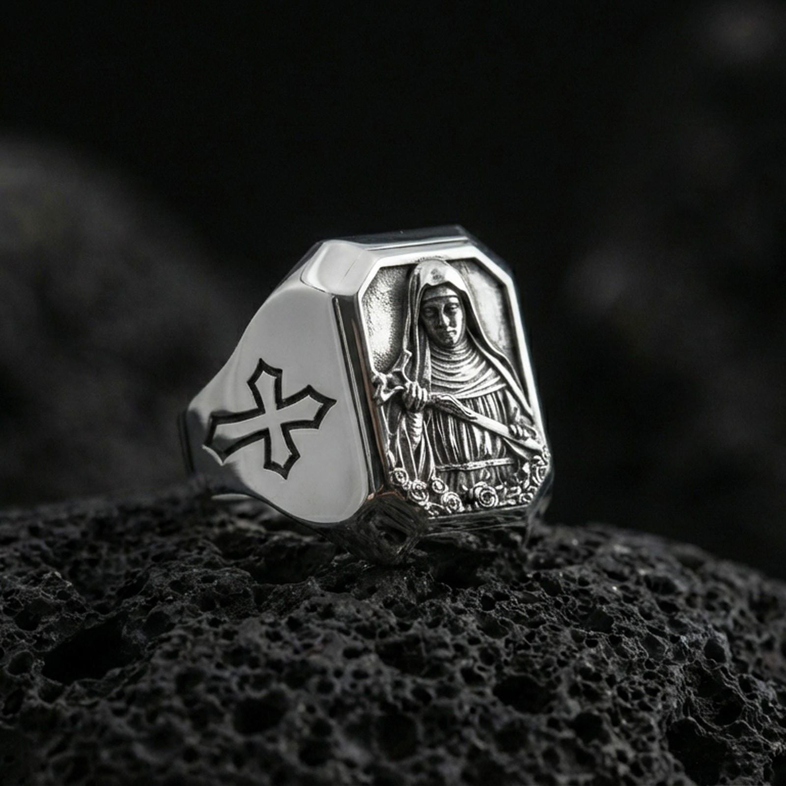 Polished silver St Rita of Cascia signet ring on porous volcanic stone, detailed saint portrait, Catholic cross ring