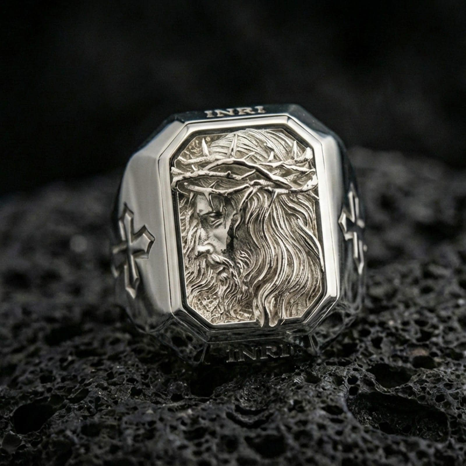 Polished silver Jesus crown of thorns signet ring on porous volcanic stone, detailed side-profile Jesus portrait, Christian ring
