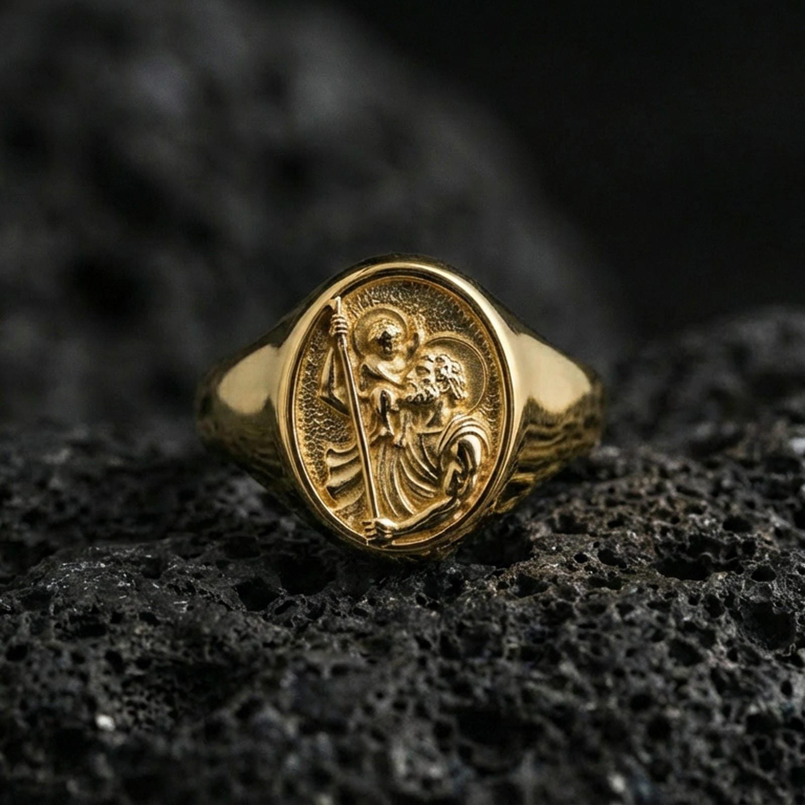 Gold plated St Christopher signet ring on dark volcanic rock, patron of travelers icon relief, faith protection ring gift