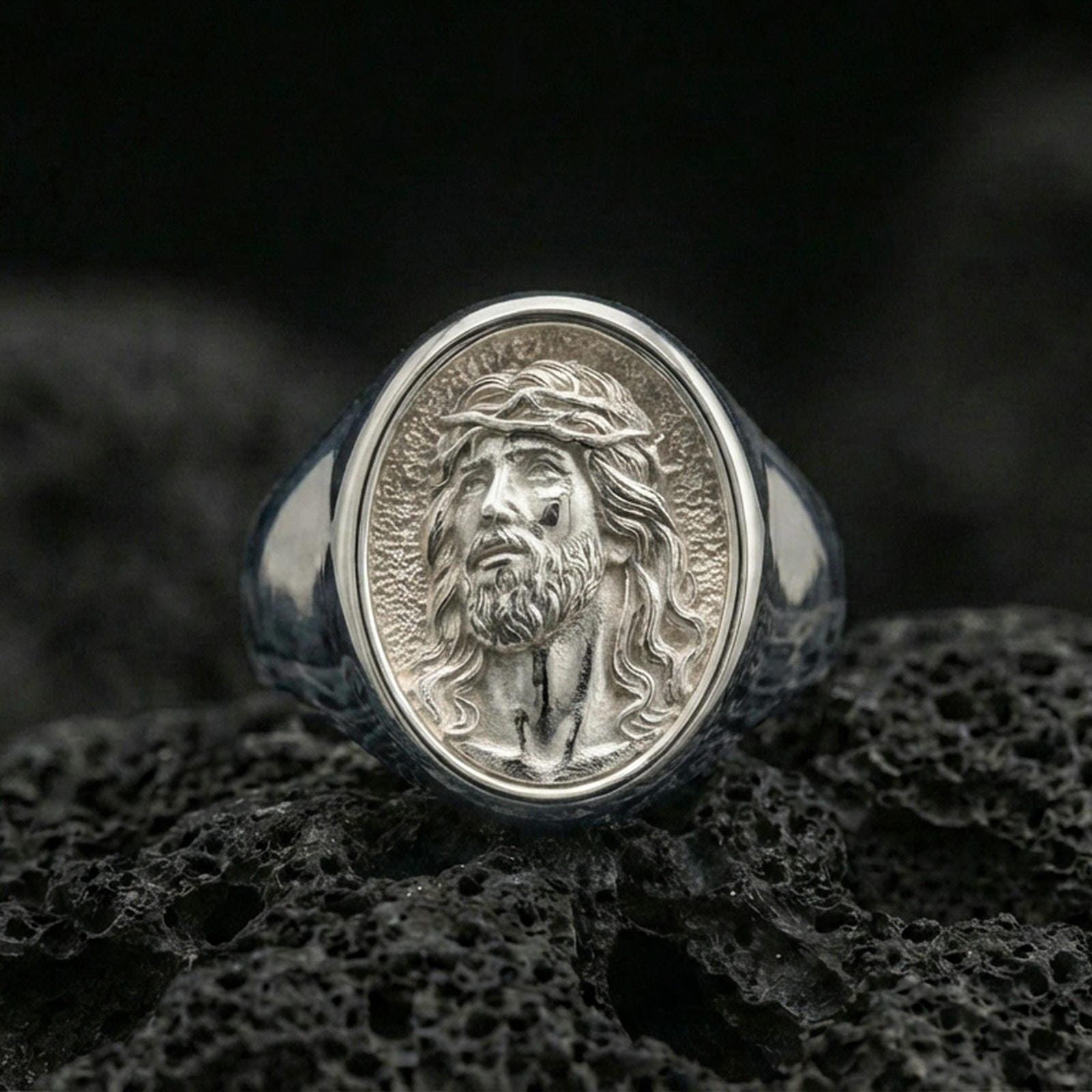 Polished silver Jesus portrait signet ring on volcanic stone, detailed Christian religious jewelry macro
