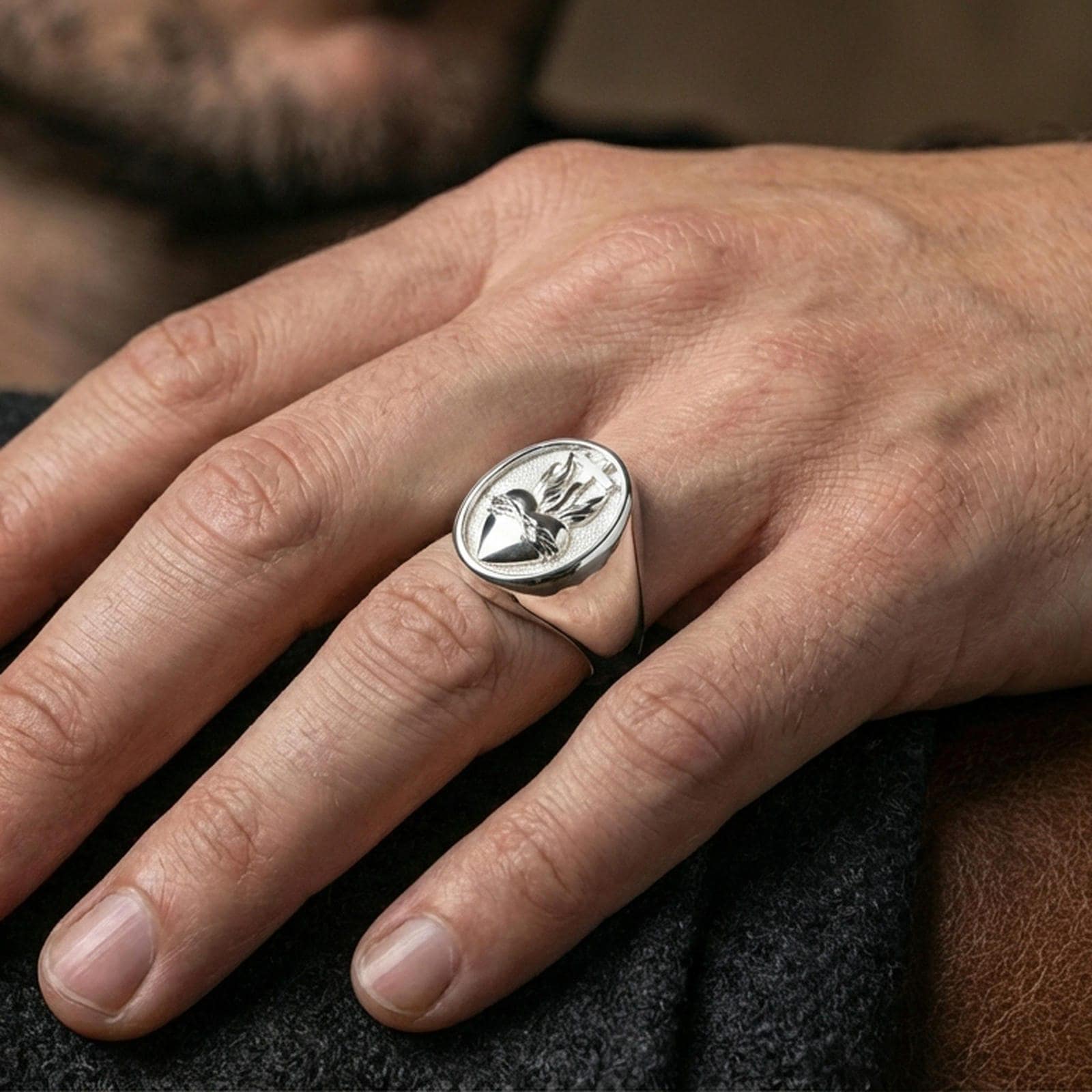 Polished silver Sacred Heart signet ring worn on finger, flaming heart relief detail, Christian faith jewelry