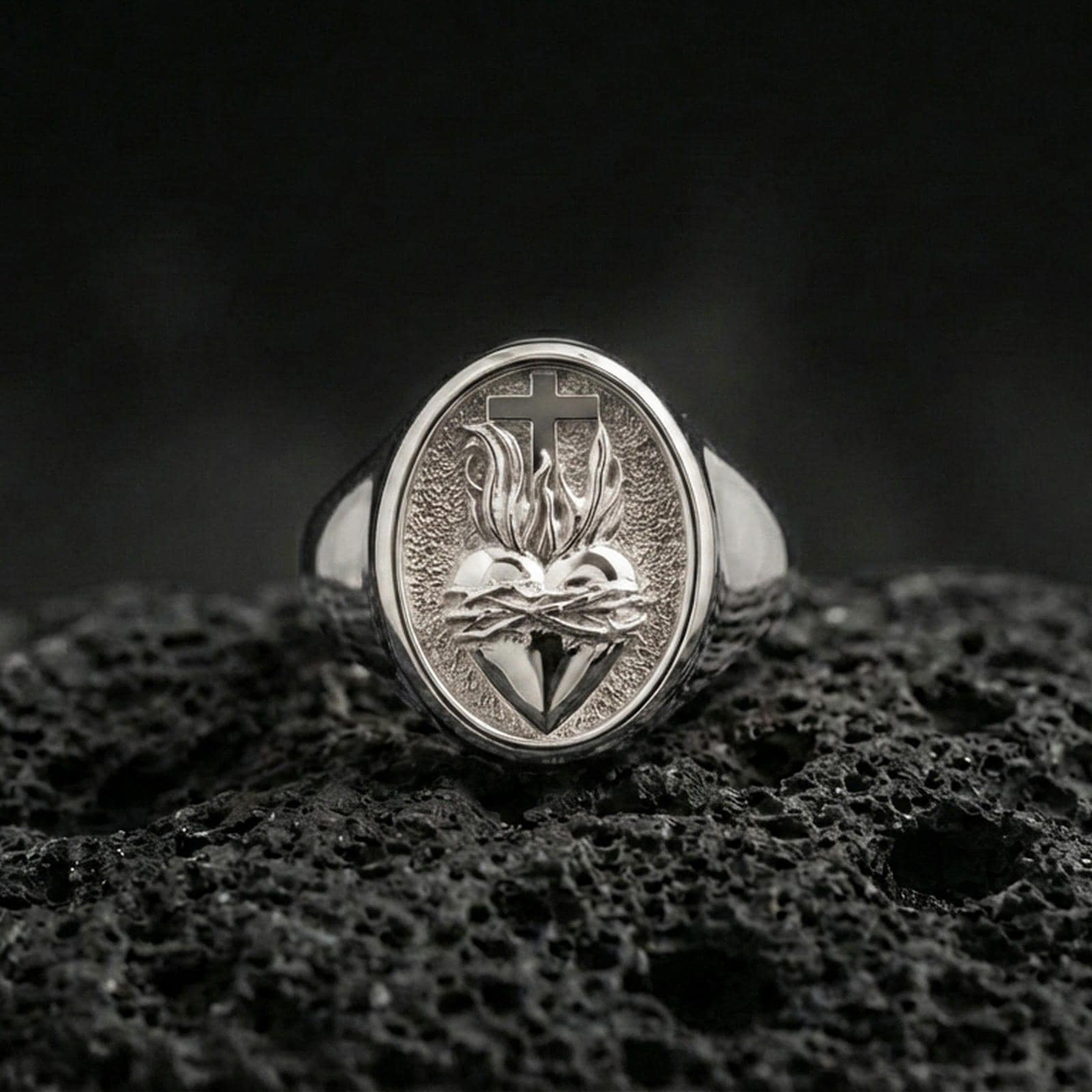 Polished silver Sacred Heart ring on porous volcanic stone, flaming heart engraving with crown of thorns, Christian ring