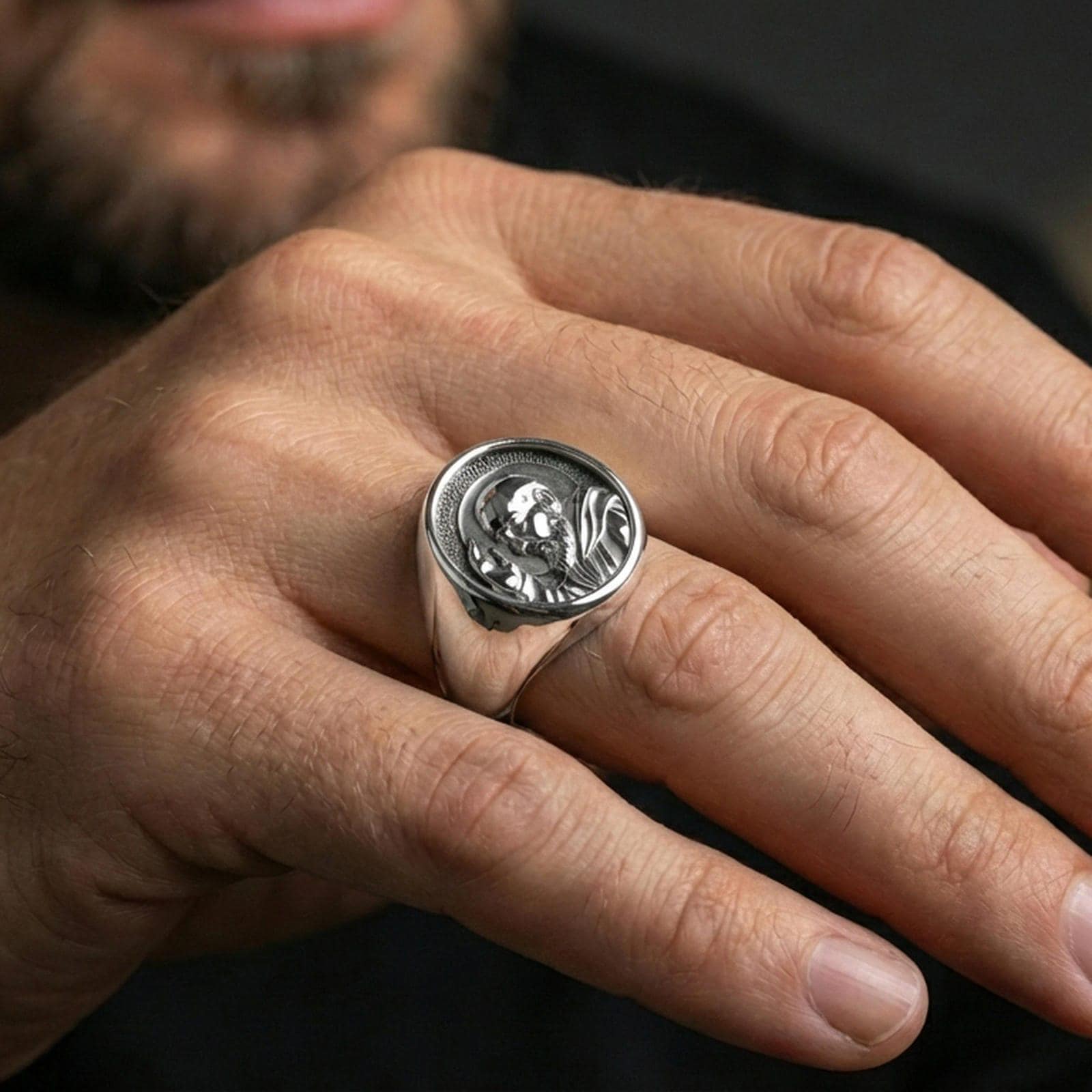 Polished silver Padre Pio signet ring worn on finger, detailed saint profile relief, faith-inspired jewelry
