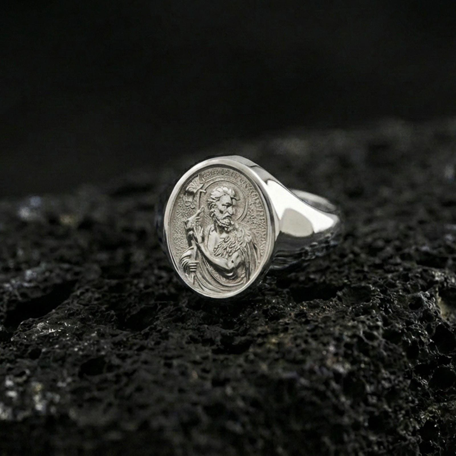 Polished silver Saint John the Baptist signet ring on porous volcanic stone, detailed saint engraving, religious signet ring