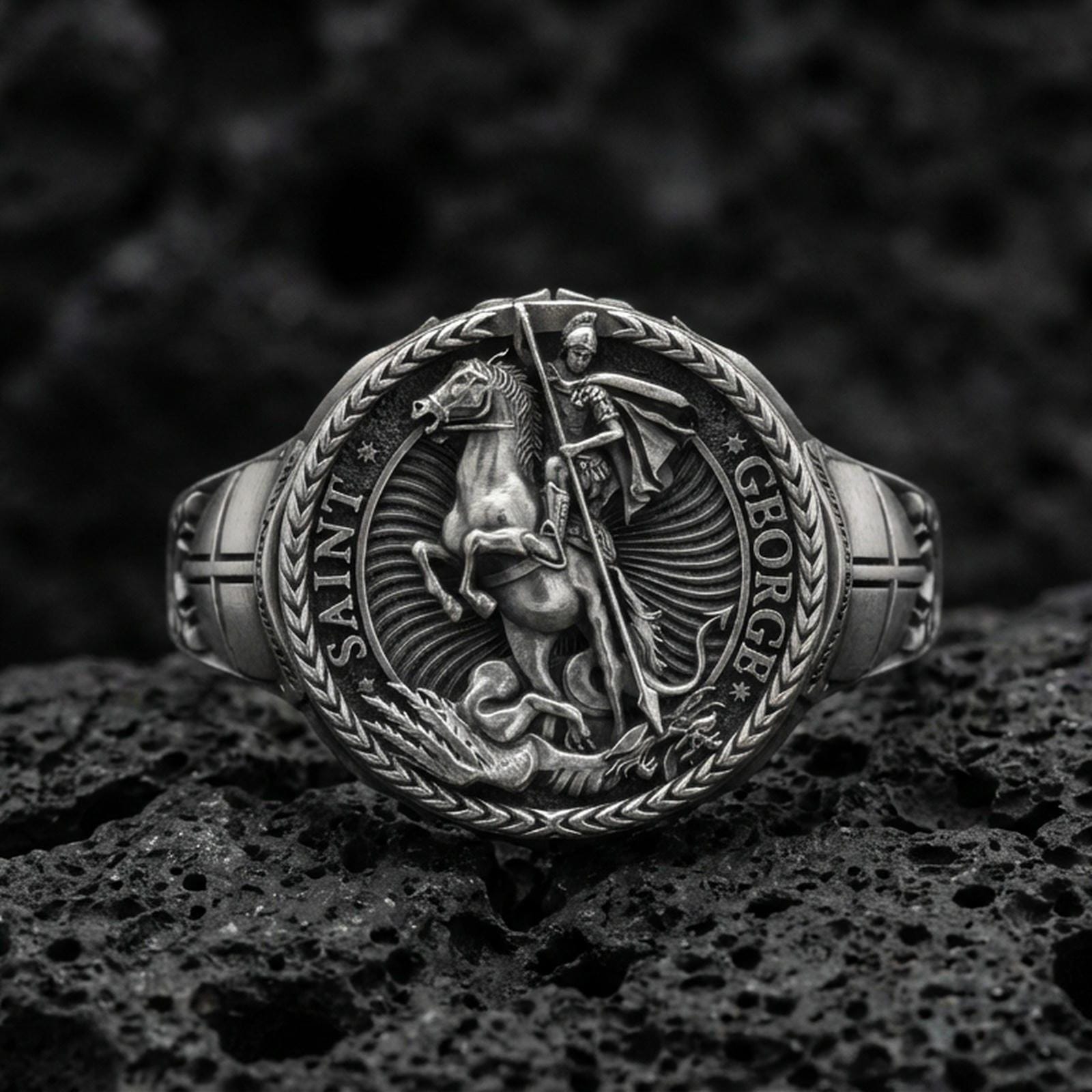Oxidized 925 sterling silver St. George and the Dragon ring on volcanic rock, medieval knight seal relief