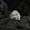 Load image into Gallery viewer, Polished silver skull mandala ring on porous volcanic stone, detailed floral engraving, biker gothic style
