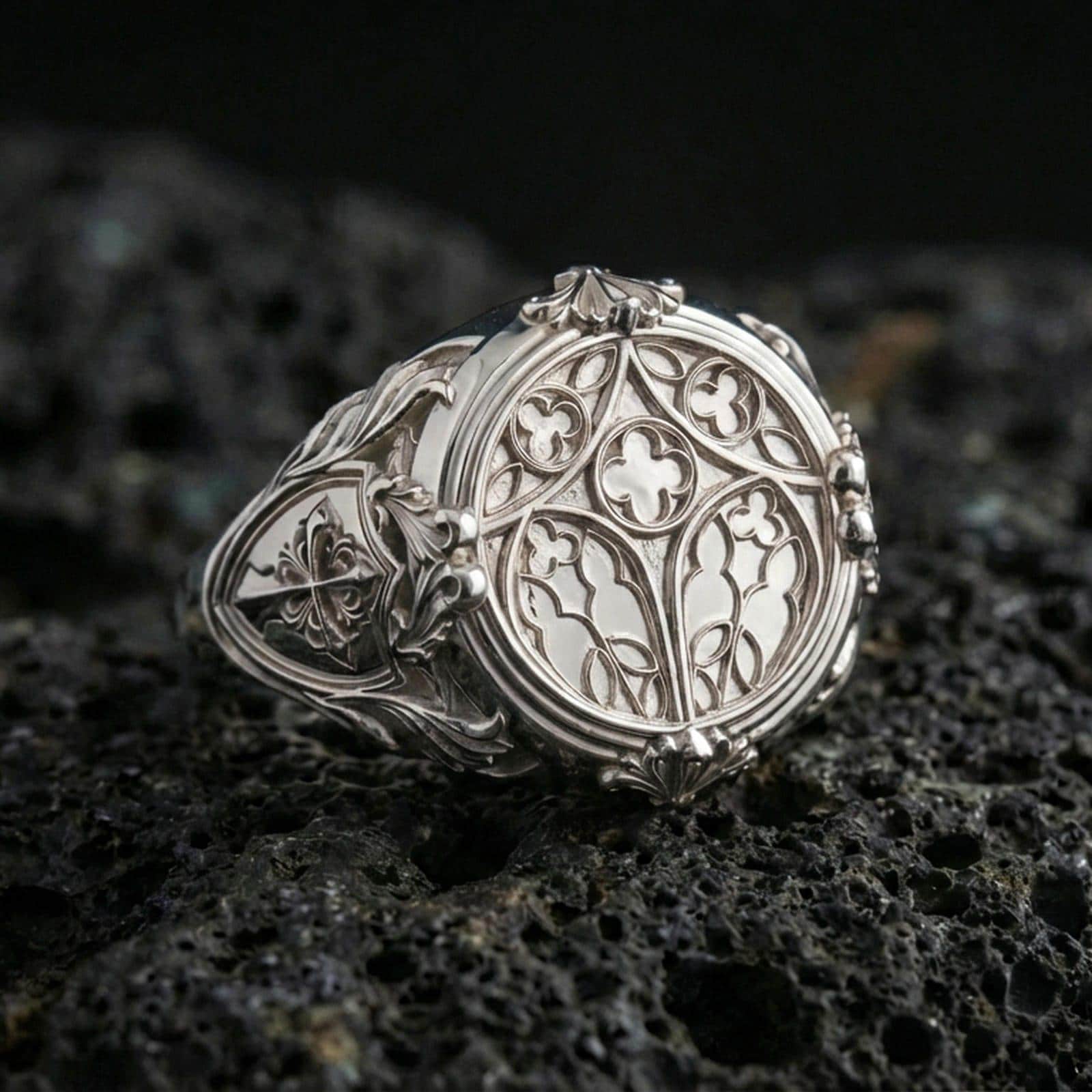 Polished silver cathedral window ring on porous volcanic stone, ornate medieval filigree, statement signet style