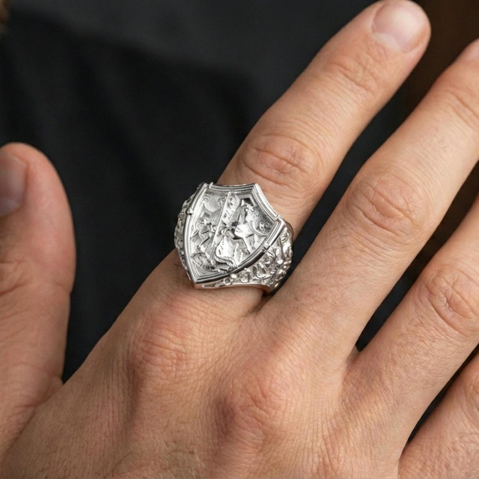 Polished silver Saint George defeating dragon ring worn on finger, detailed knight shield relief, classic statement ring