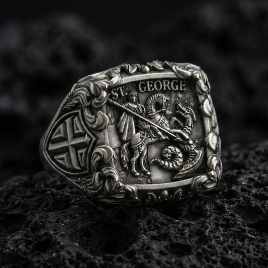 Oxidized 925 sterling silver St George dragon slayer ring on volcanic rock, ornate knight signet with Celtic cross side