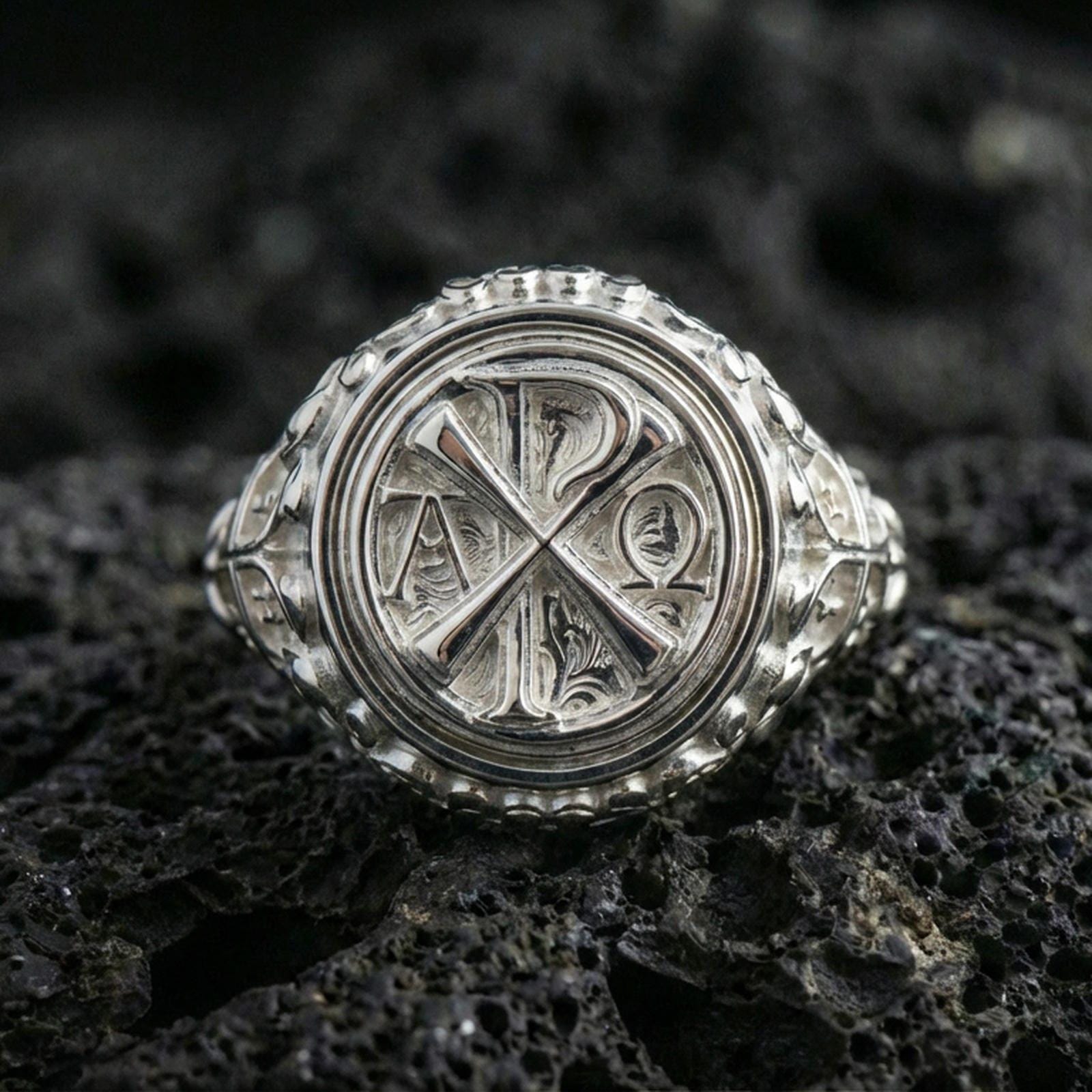 Polished silver Chi Rho Alpha Omega signet ring on porous volcanic stone, raised Christian monogram, bold faith ring
