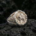 Load image into Gallery viewer, Polished silver Agnus Dei seal ring on porous volcanic stone, Lamb of God emblem with Latin text, ornate cross side detail
