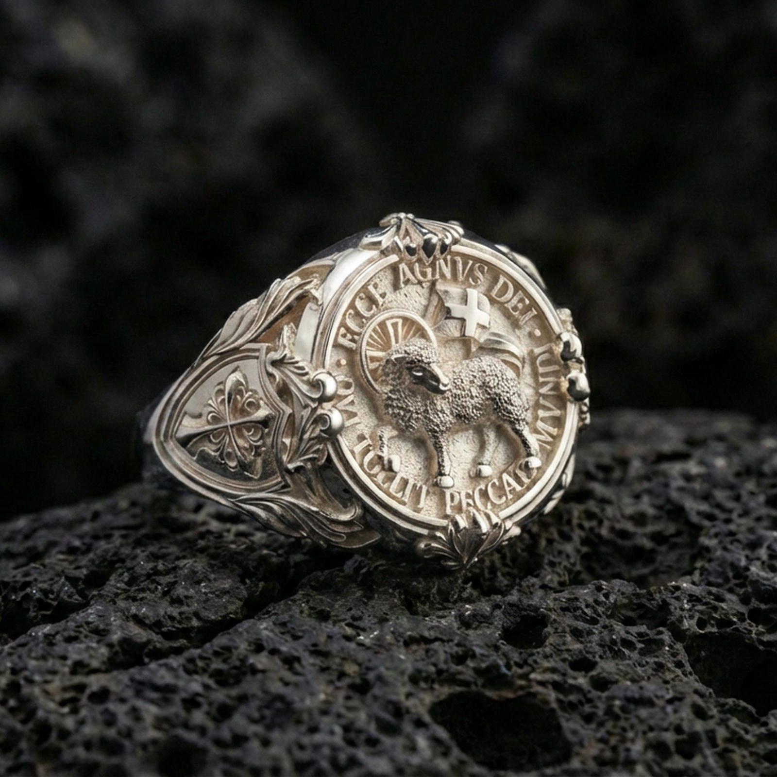 Polished silver Agnus Dei seal ring on porous volcanic stone, Lamb of God emblem with Latin text, ornate cross side detail