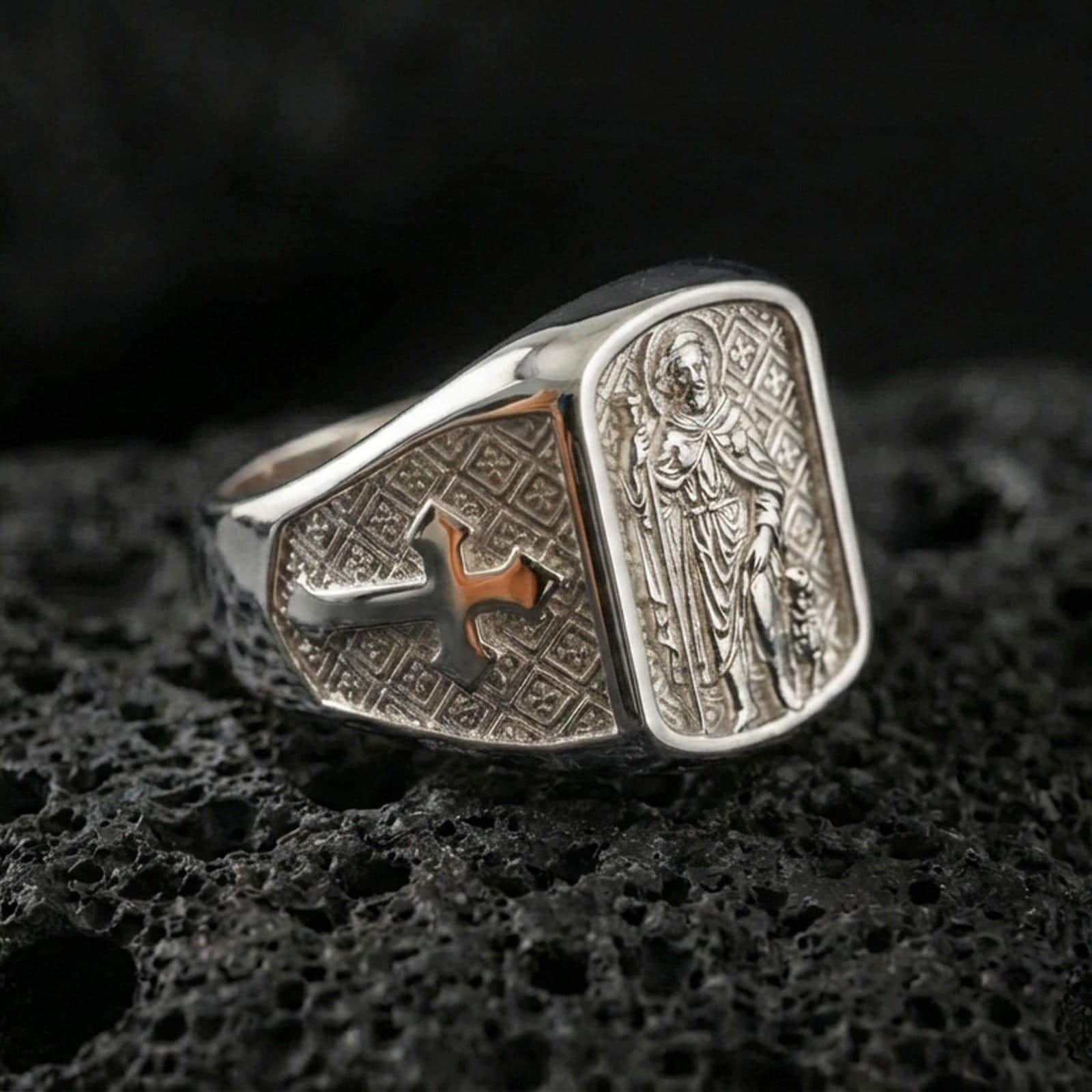 Polished silver Saint Roch signet ring on porous volcanic stone, religious saint medal relief, protection and healing symbol design